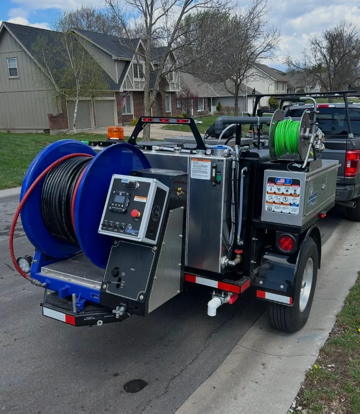 Pro Jet trailer-mounted hydro jetting unit with hose reel and control panel on a residential street